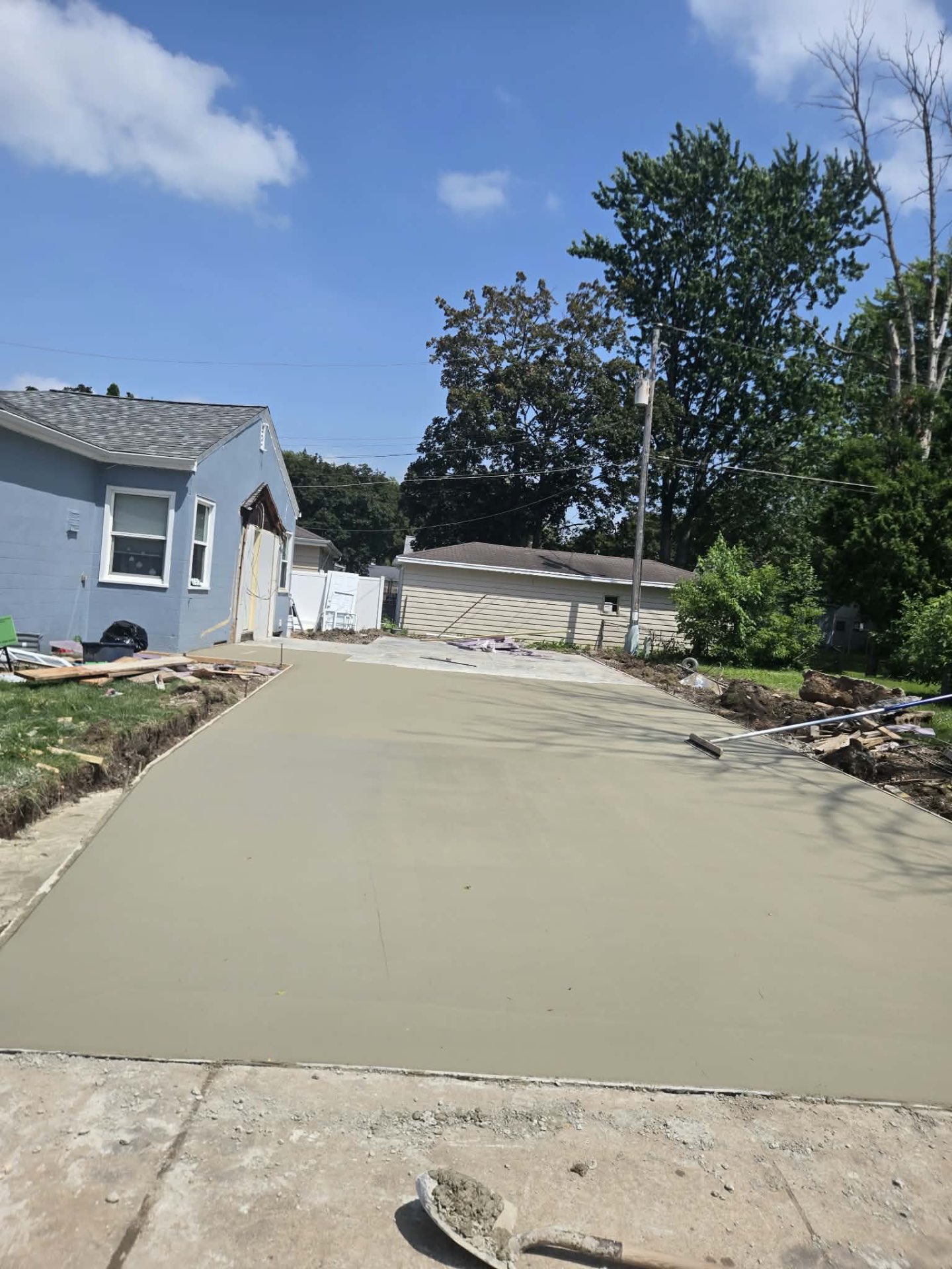 Freshly poured and floated concrete driveway running alongside a home