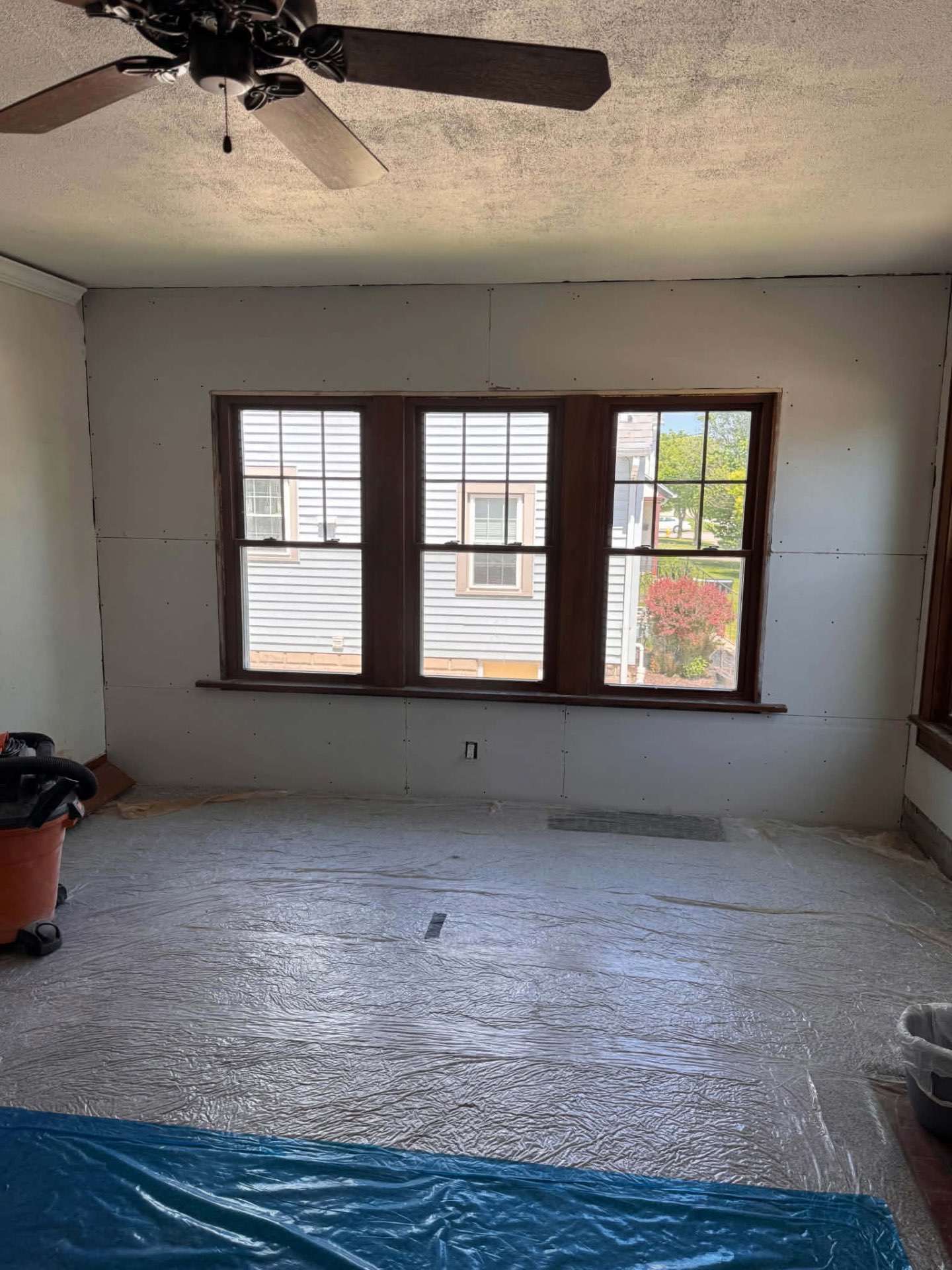Living room with new drywall installed and floors masked off for finishing