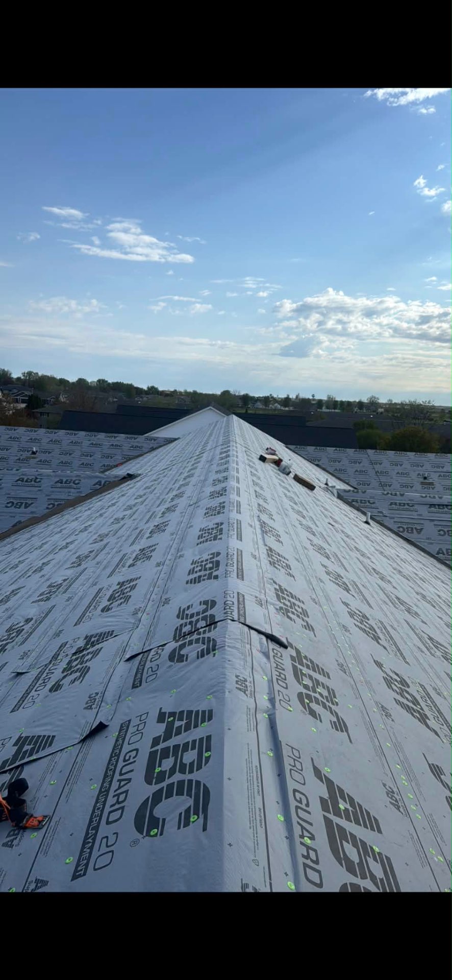 Long roof ridge covered in synthetic roofing underlayment before shingles