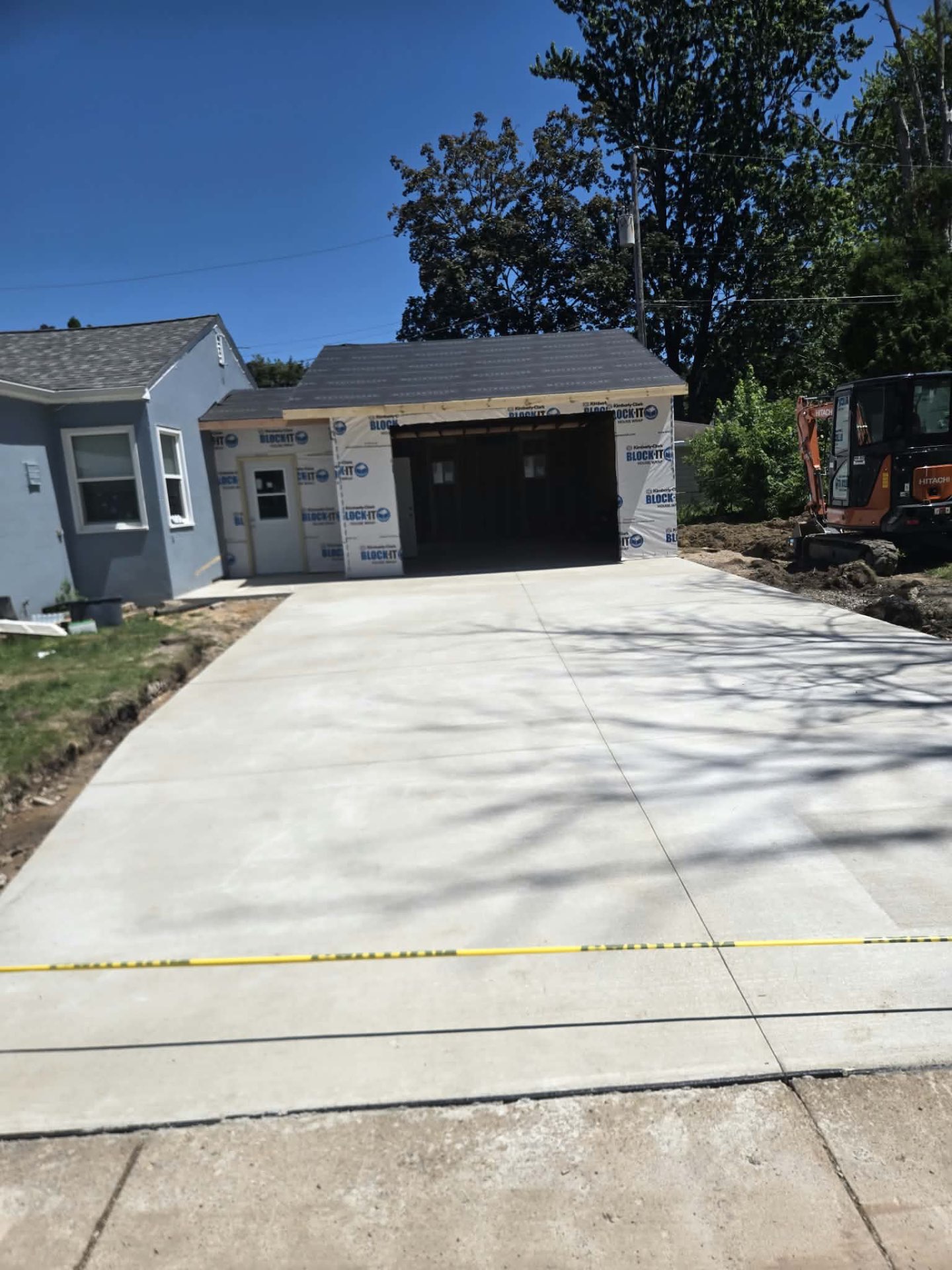 Finished wide concrete driveway leading into a newly framed garage